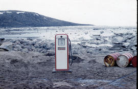 Photograph of an Esso gas pump and three barrels