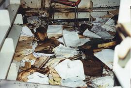 Photograph of fire damaged documents piled on the floor
