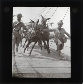 Photograph of unidentified soldiers crossing bridge with cart and donkeys