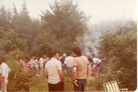 Photograph of Nolan Reilly and several other unidentified attendees conversing near a barbecue at...