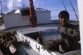 Photograph of a man emptying a bucket on a small boat