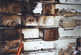 Photograph of fire damaged shelves and documents