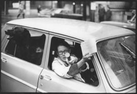 Photograph of an unidentified pro-war demonstrator gesturing out of the passenger seat of a car d...