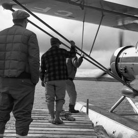 Photograph of three men from St. Felicien Air Serivces next to a sea plane in northern Quebec