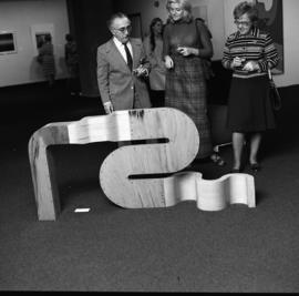 Photograph of three unidentified people with a sculpture