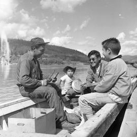 Photograph of Arthur Percy, a man, and two boys on a boat on the Yukon River