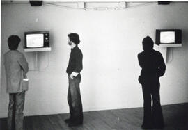 Photograph of three people watching televisions in the gallery at the Centre for Art Tapes