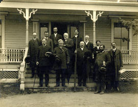 Photograph of 12 unknown individuals on the steps of a house