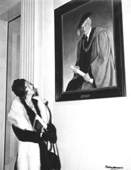 Photograph of Lady Dunn looking at a portrait of Sir James Dunn