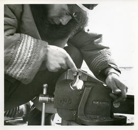 Photograph of a man working with a vice in Fort Chimo, Quebec