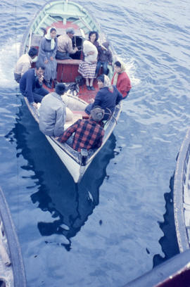 Photograph of several people traveling with a new baby in a small boat in Hopedale, Newfoundland ...