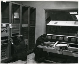 Photograph of two men installing equipment in the television control room