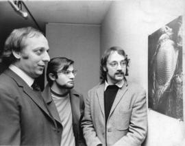 Photograph of three unidentified men looking at a photo