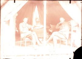 Two officers sitting inside of a tent