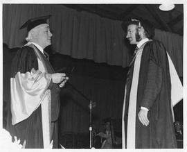 Photograph of Henry Hicks presenting a medal to a graduate