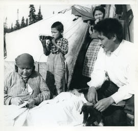 Photograph of four people and a dog by a tent in Davis Inlet, Newfoundland and Labrador