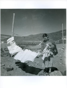 Photograph of an unidentified girl putting laundry on a clothesline