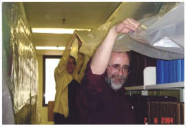 Photograph of Betty Sutherland and Patrick Ellis holding tarps after the Kellogg Library flood 2004