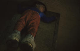 Photograph of a child with fur boots sleeping on the floor