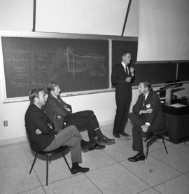 Photograph of four unidentified people in a classroom