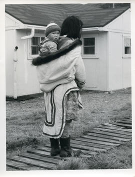 Photograph of a woman carrying a baby in her parka in Sugluk, Quebec