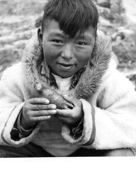 Photograph of a boy holding a carving in Cape Dorset, Northwest Territories