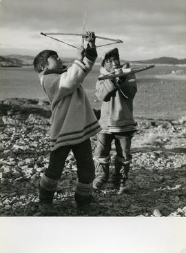 Photograph of two boys playing with toy bows and arrows in Cape Dorset, Northwest Territories