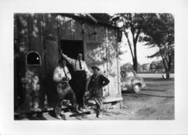 Photograph of three men standing in the door of a shed