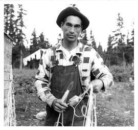 Photograph of an unidentified man wearing a plaid shirt and holding a seal net