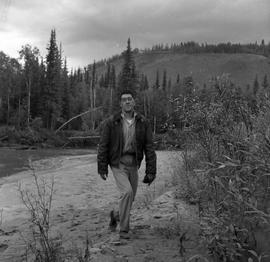 Photograph of Dick Field walking by a river near Dawson City, Yukon
