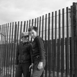 Photograph of Jackie Koneak and a friend standing by a fence in northern Quebec