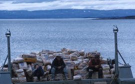 Photograph of three men sitting on a load of sugar in Frobisher Bay, Northwest Territories