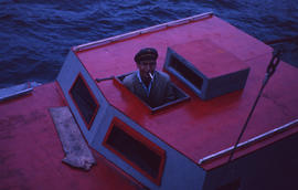 Photograph of a man looking out of the cabin of his boat in North West River, Newfoundland and La...