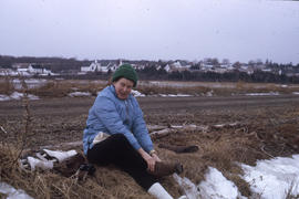 Photograph of Barbara Hinds sitting on the ground and putting her boots on