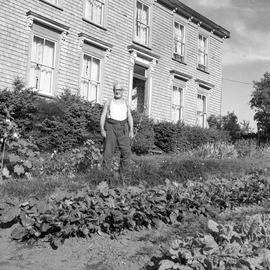 Photograph of Mr. Farrant standing in a garden in front of a house