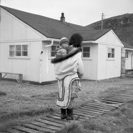 Photograph of and unidentified woman carrying a baby in Sugluk, Quebec