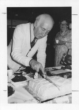 Photograph of Jim Campbell cutting a cake
