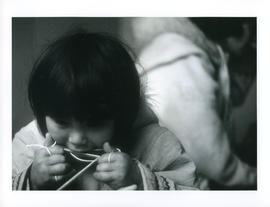 Photograph of an unidentified girl making something with string