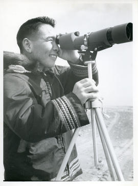 Photograph of a man looking through a telescope