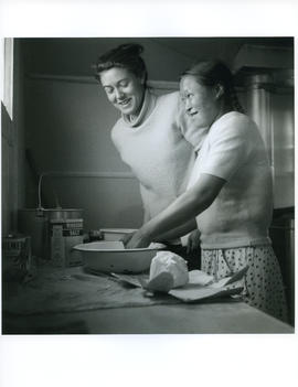 Photograph of Barbara Hinds and an unidentified girl making something in a kitchen