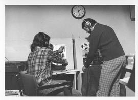 Photograph of two unidentified people with audiovisual equipment