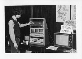 Photograph of an unidentified person looking at a display by T.V. services