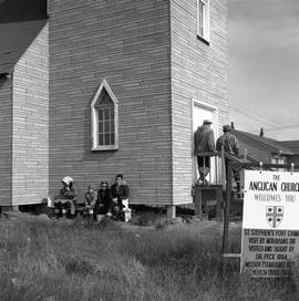 Photograph of several people waiting outside of the St. Stephen's Anglican church in Fort Chimo, ...