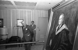 Photograph of an unidentified person looking at a painting of Chester Stewart