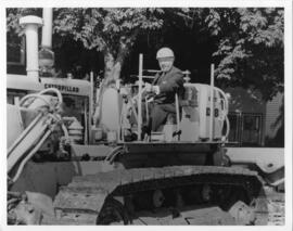 Photograph and photographic negative of President Henry Hicks on a bulldozer