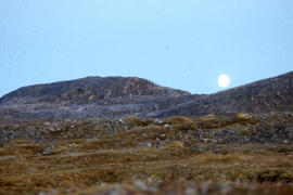 Photograph of the moon rising over a hill in Cape Dorset, Northwest Territories