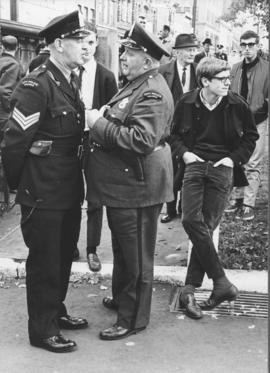 Photograph of two police officers conversing in Halifax's Grand Parade while, off-camera, marcher...