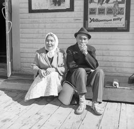 Photograph of a man and a woman sitting in front of a building in Dawson City, Yukon