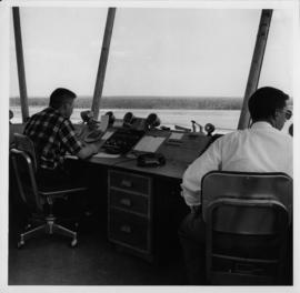Photograph of two unidentified people sitting at an airport control tower