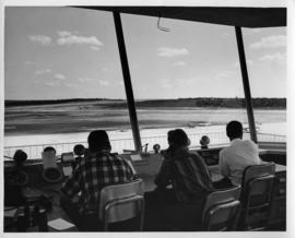 Photograph of three unidentified people sitting at an airport control tower